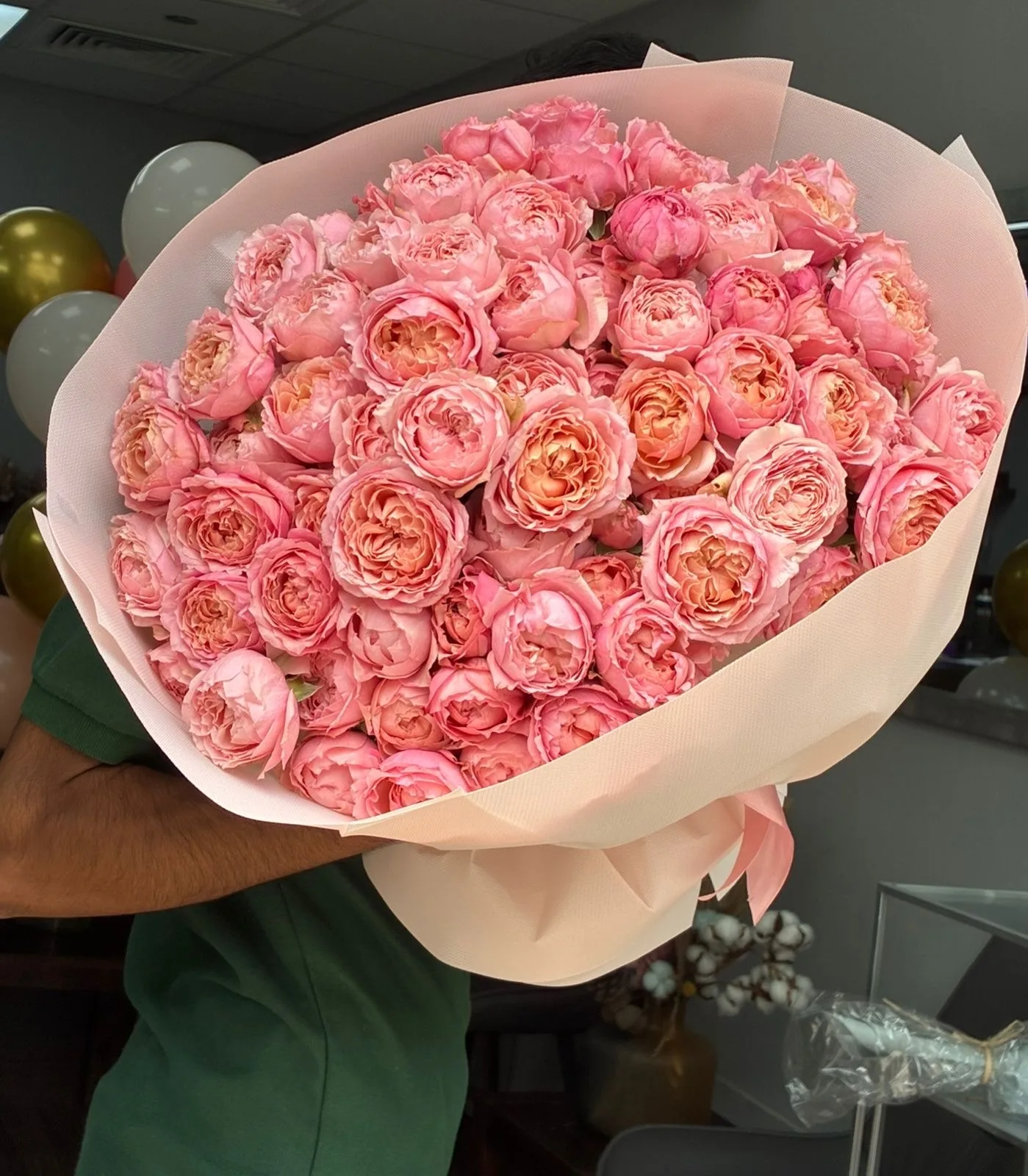 A full bouquet of pink garden spray roses wrapped in blush paper