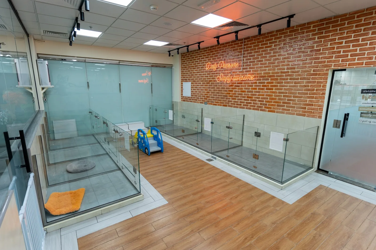 Glass-fronted private boarding suites with a brick feature wall