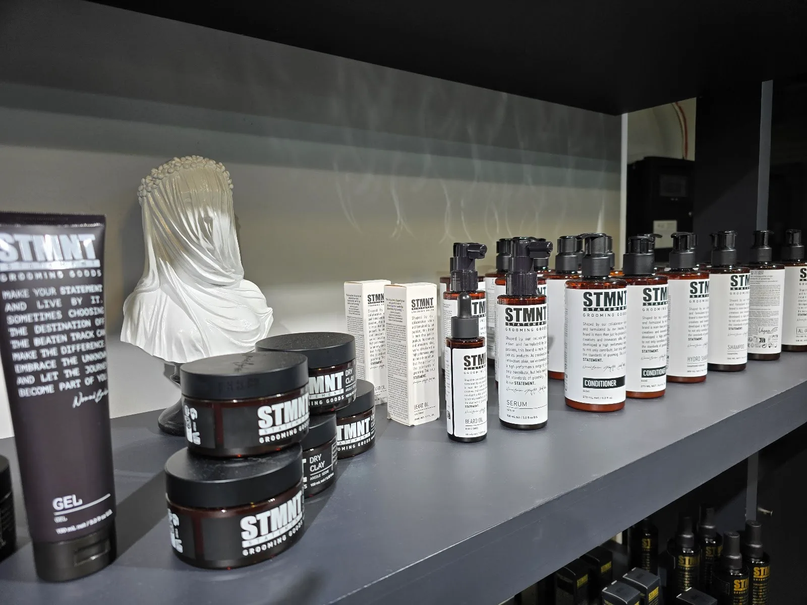STMNT grooming products lined up on a shelf in the salon