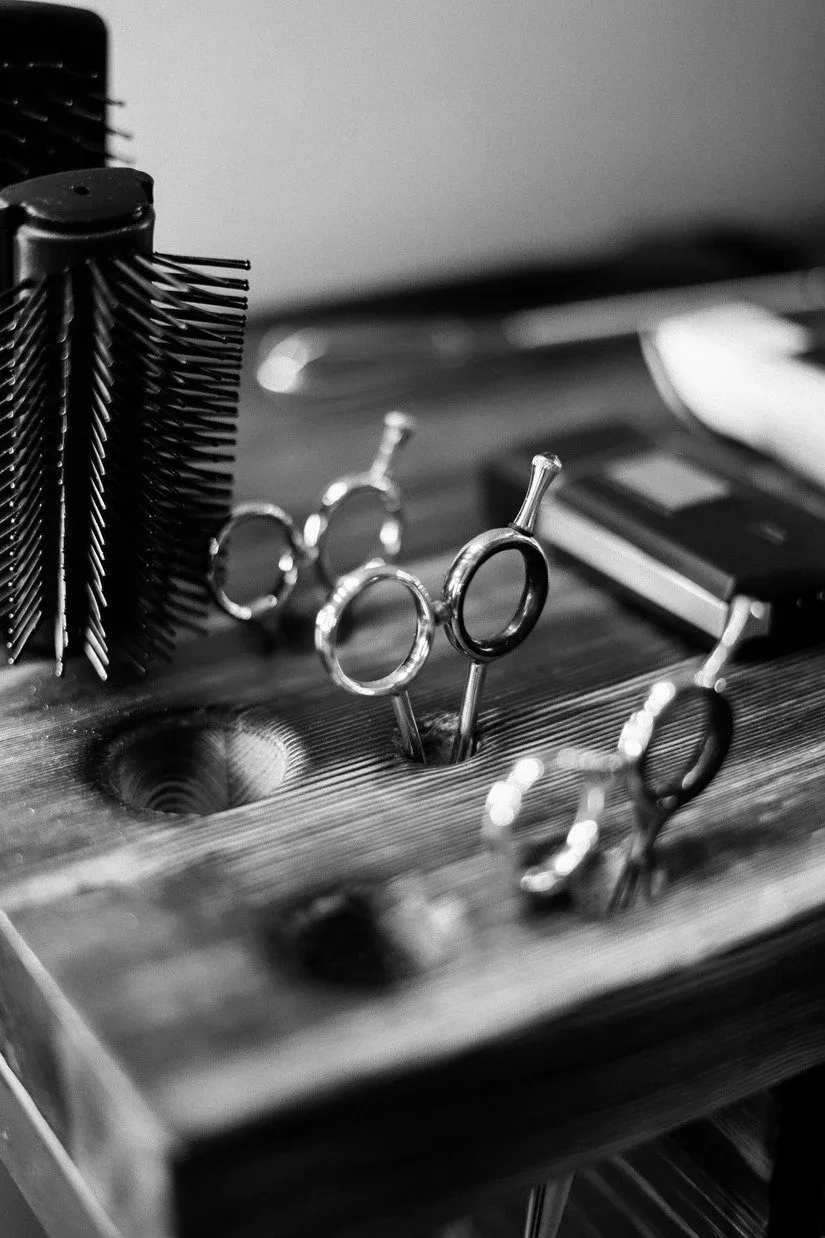 Barber scissors resting on a wooden stand