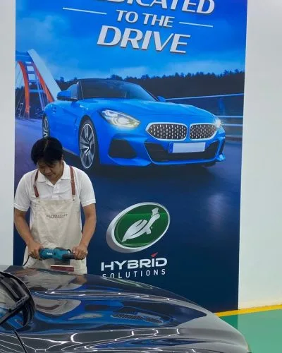 Technician machine polishing a blue car