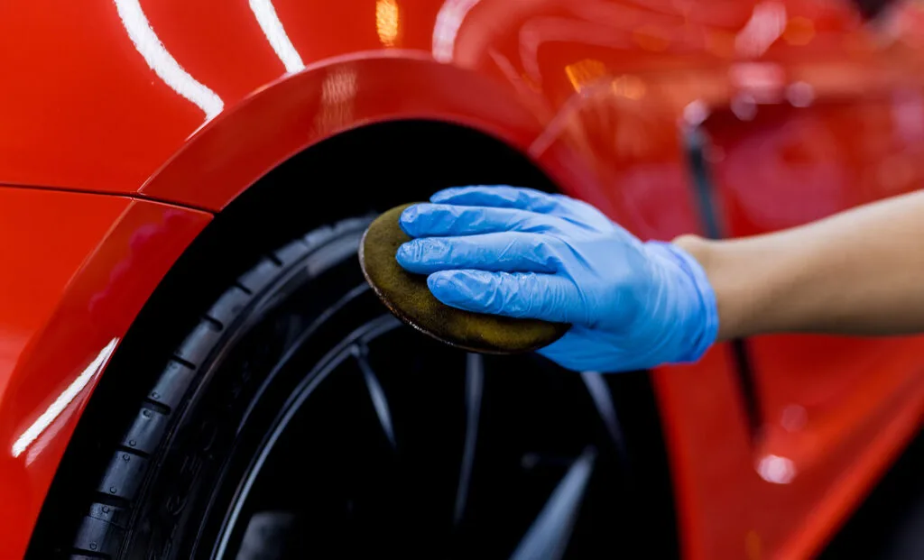Gloved hand cleaning an alloy wheel and tyre