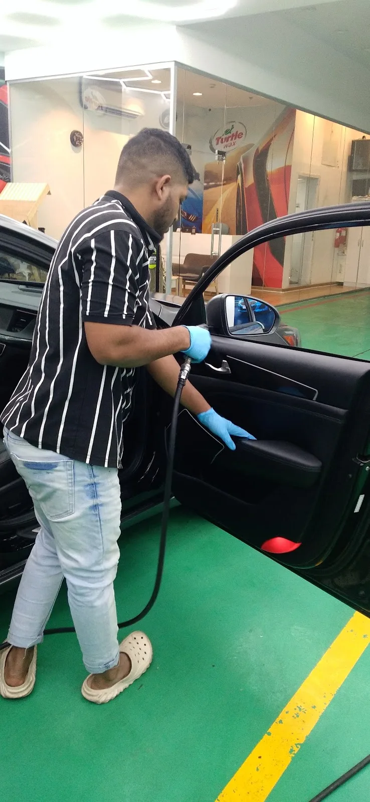 Technician steam cleaning a car door panel interior