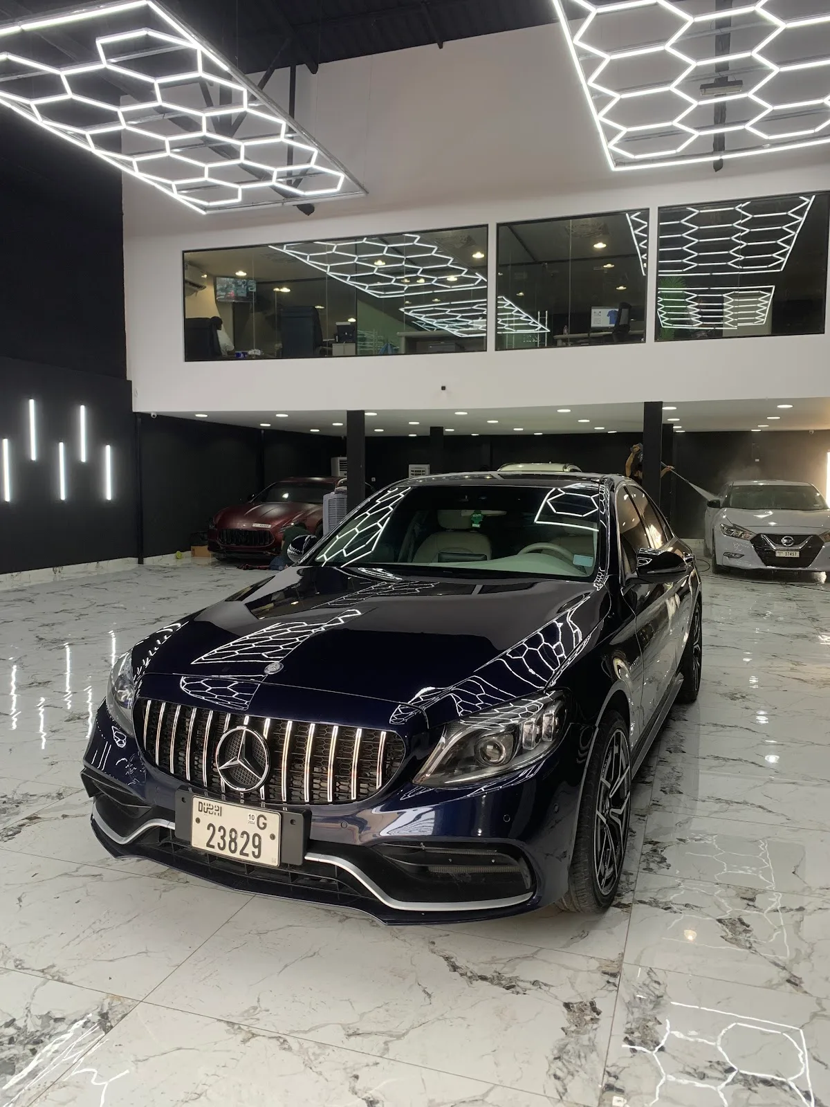 A navy Mercedes-AMG saloon detailed to a deep gloss under Elite Crystal's hexagon LED ceiling