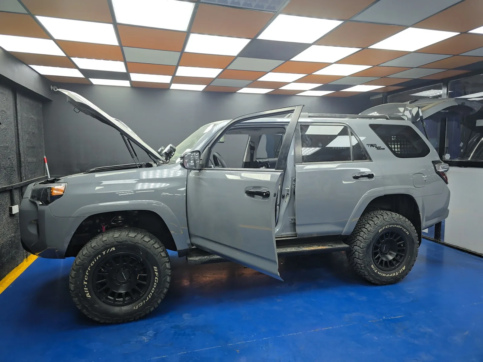 Grey lifted Toyota 4Runner TRD with door and bonnet open in a service bay