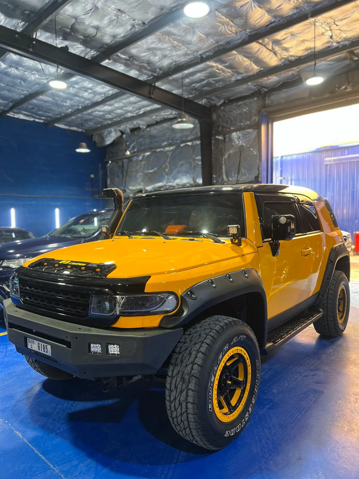 Yellow Toyota FJ Cruiser with off-road tyres in the workshop
