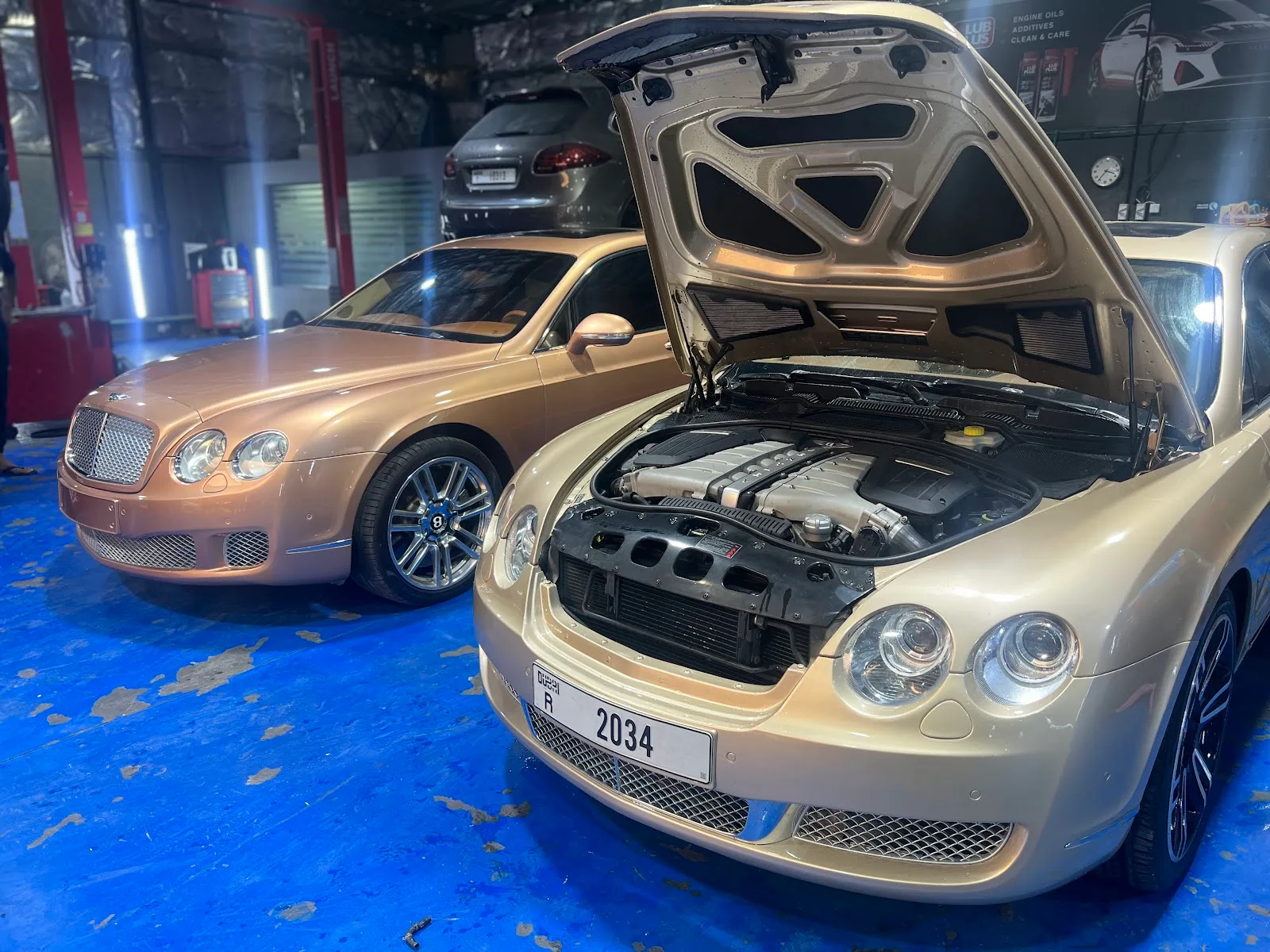 Two Bentley Continental cars being serviced, one with the bonnet open