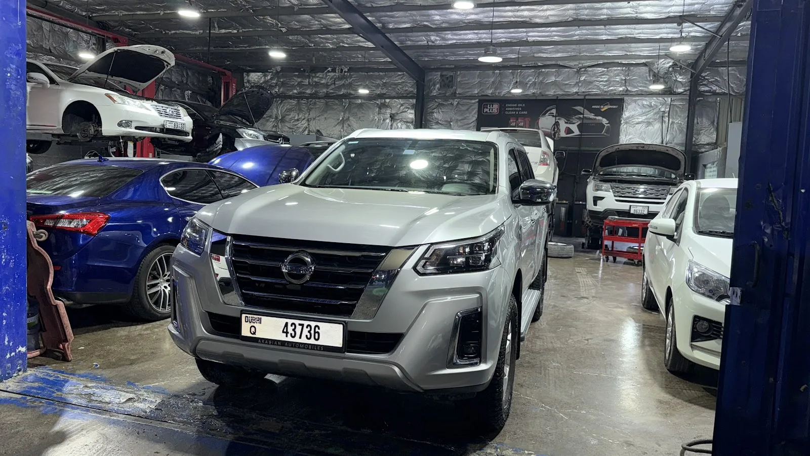 Silver pickup and other vehicles inside the Al Bedayer Garage workshop