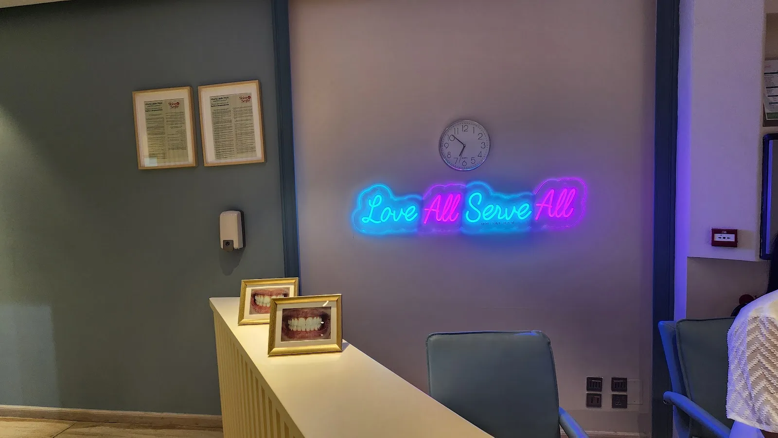 Neon Love All Serve All sign inside the clinic