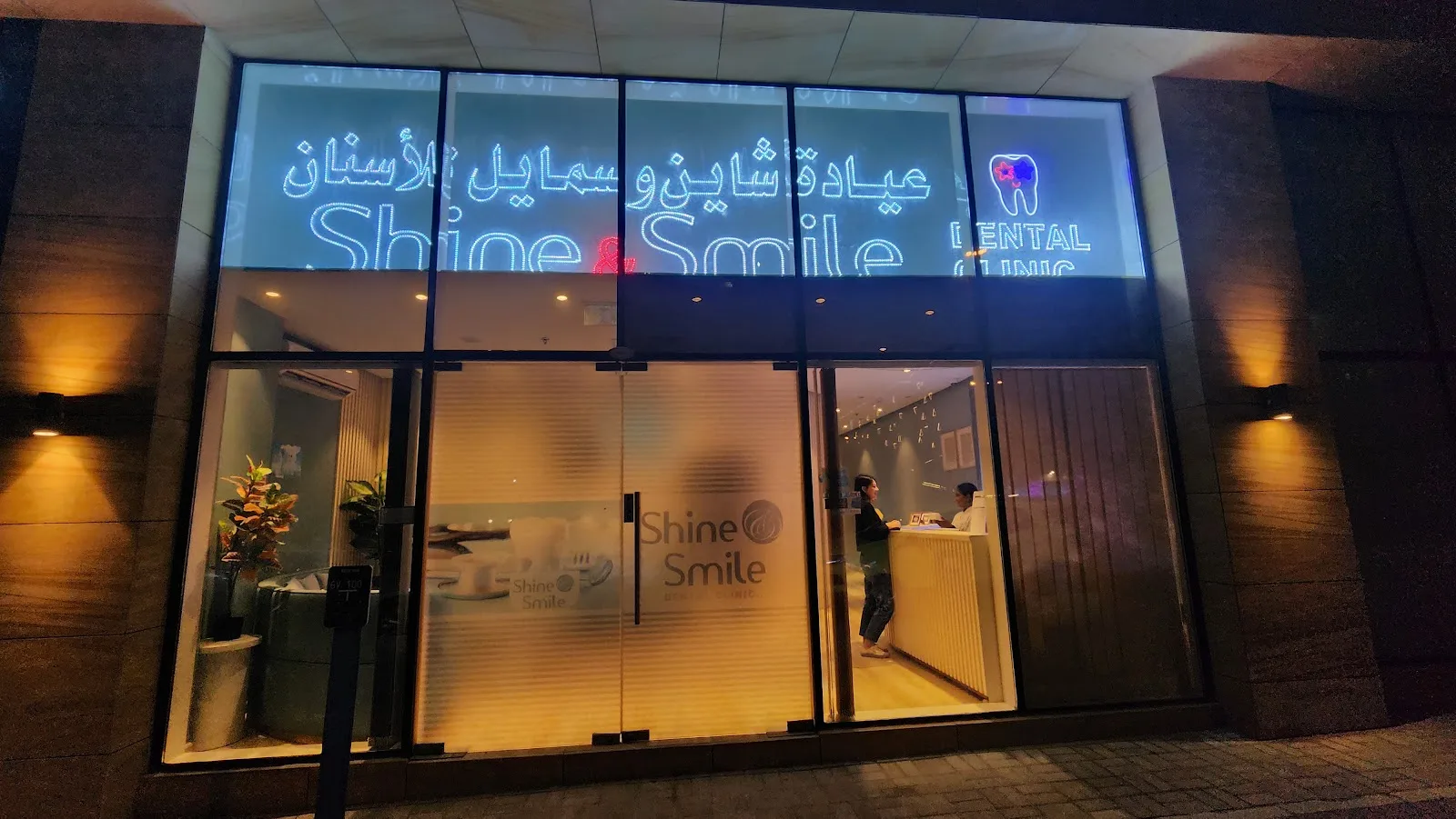 Shine and Smile Dental Clinic illuminated storefront at night in JVC