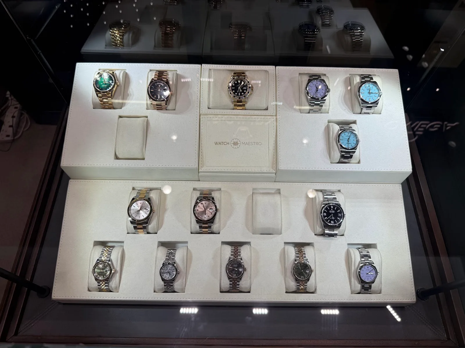 Display case filled with luxury watches on cushions, with a WatchMaestro tray