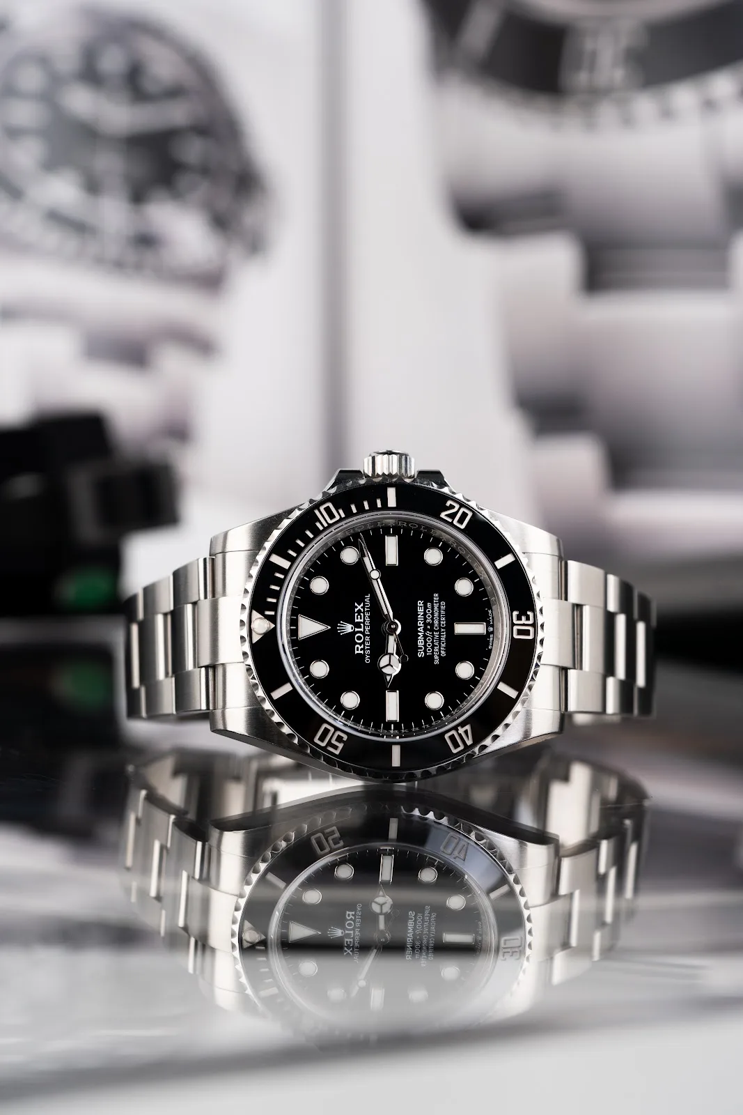 Stainless steel Rolex Submariner with black dial and bezel, on a reflective surface