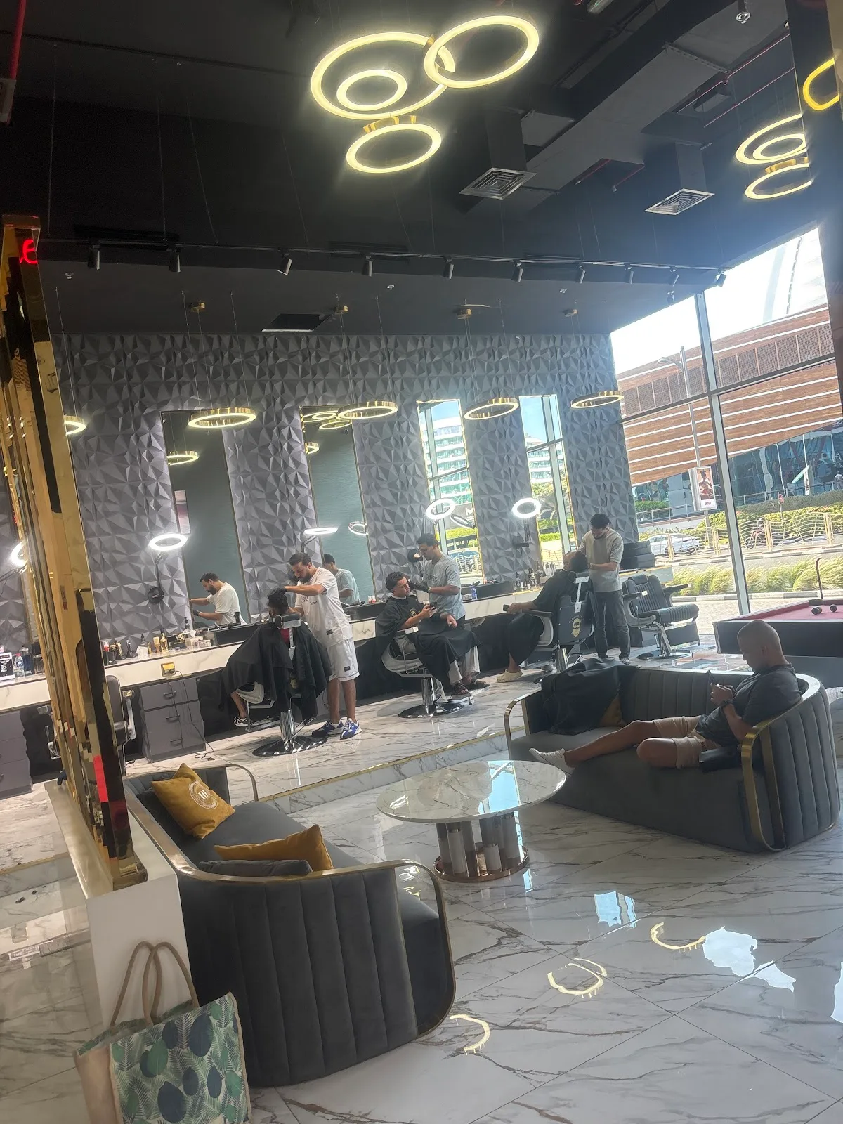 The Barber Club Dubai lounge — ring-light fixtures, barber chairs and marble floors