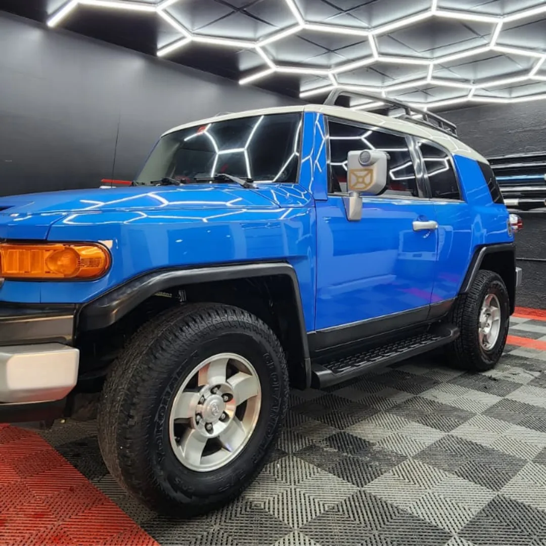 A blue Toyota FJ Cruiser under the honeycomb LED ceiling