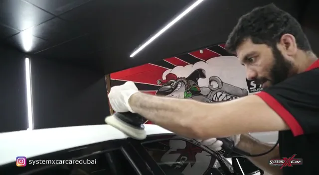 Technician machine-polishing a car panel at System X Car Care