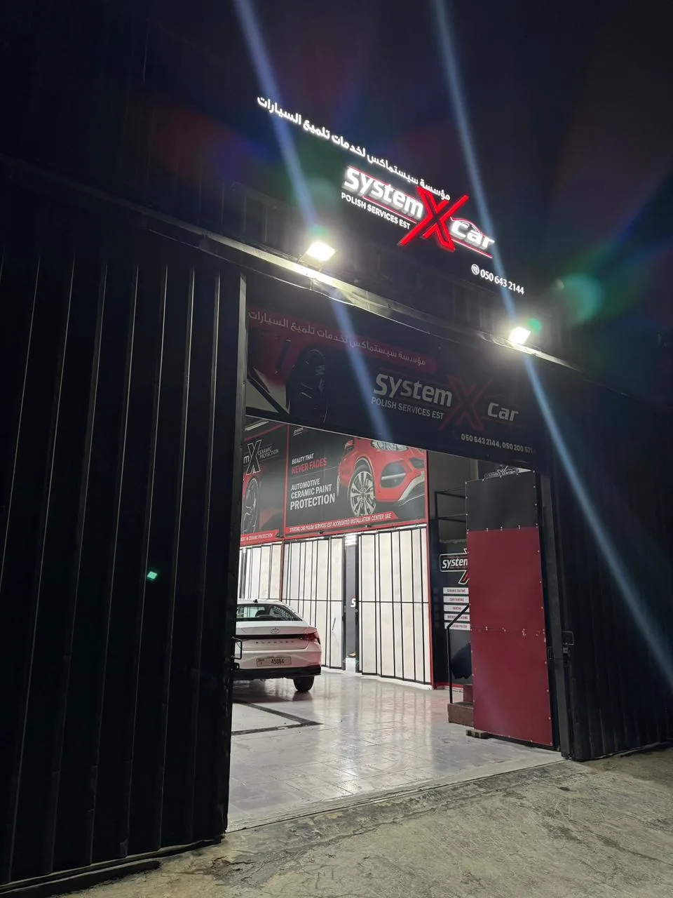 The lit System X Car Polish Services storefront in Al Quoz at night