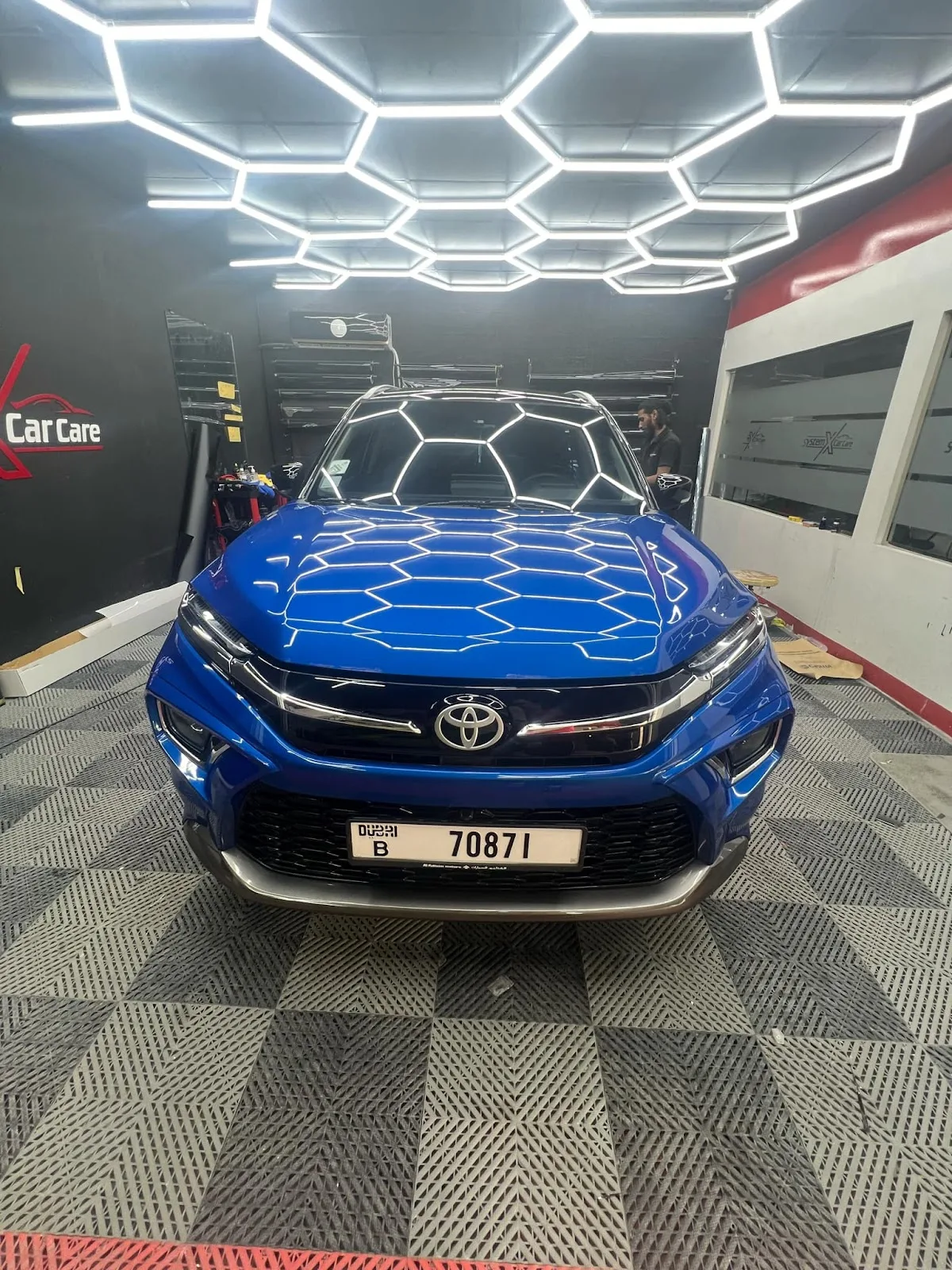 A blue car under the hexagonal bay lighting
