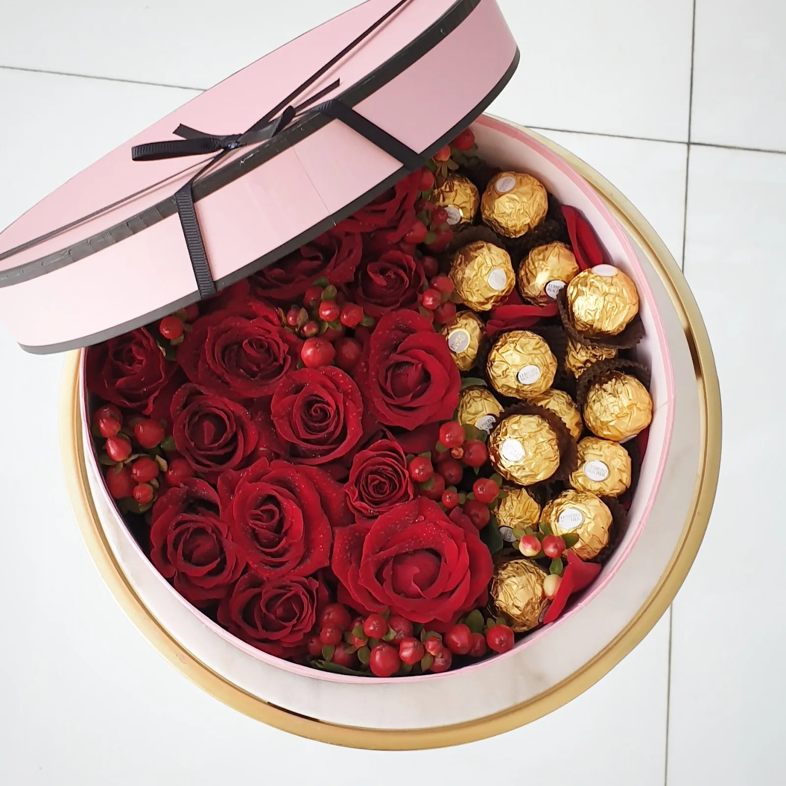 Round pink gift box with red roses and chocolates