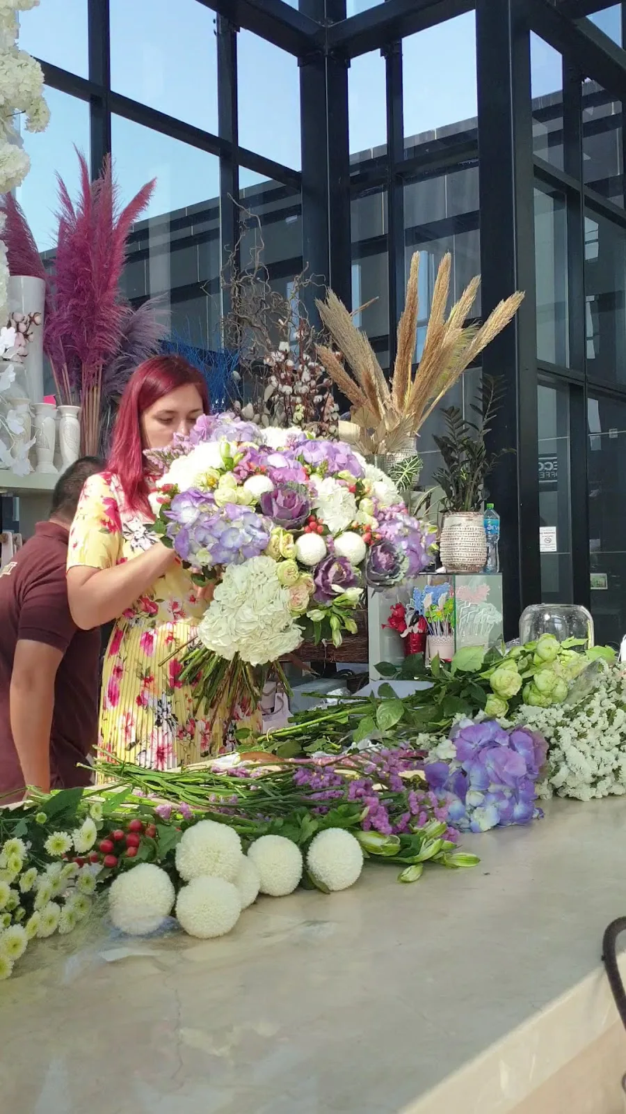 A florist arranging a large bouquet at the shop workbench