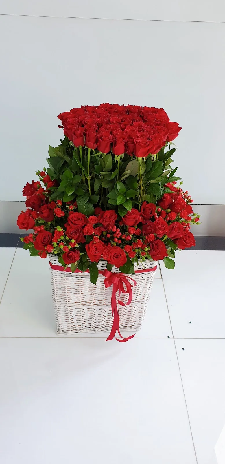 Tall basket arrangement of red roses with a red ribbon