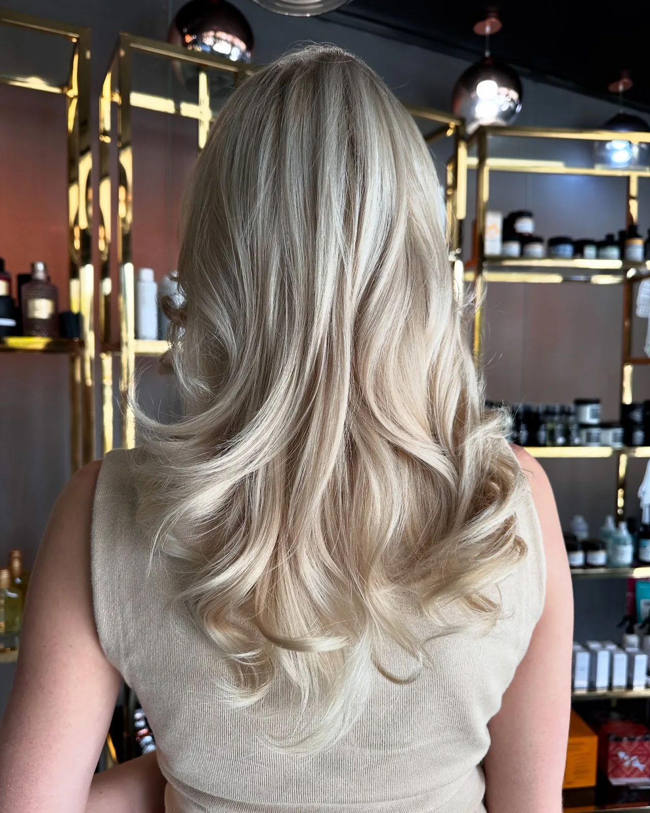 Blonde balayage with soft curls, viewed from behind