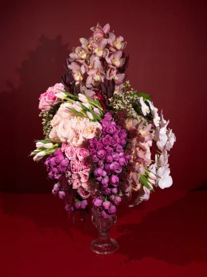 Tall cascading arrangement of orchids, roses and stocks in soft pinks and mauves