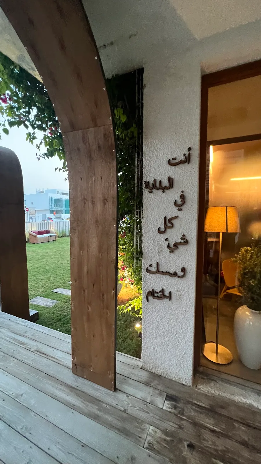 The entrance to the Wud space at dusk, with Arabic lettering on a textured wall and a warm interior glow