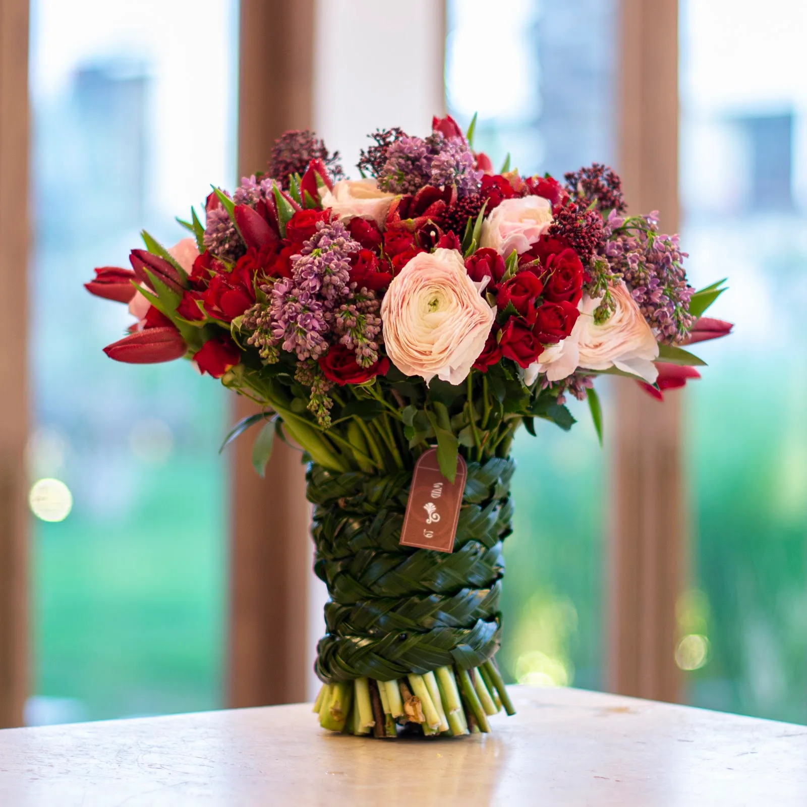 Bouquet of red, blush and lilac flowers hand-tied in a woven leaf wrap