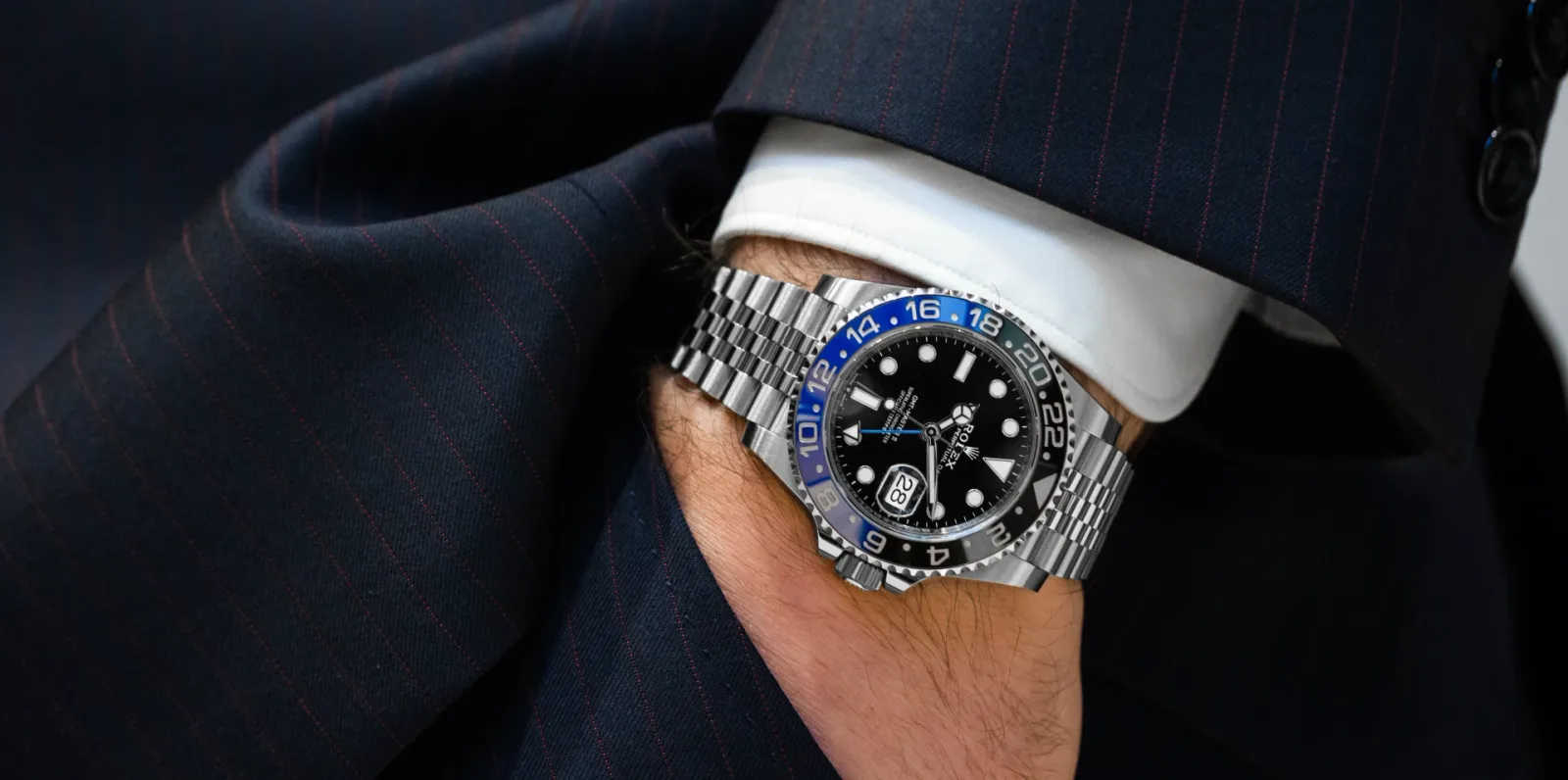 A steel sports watch worn on the wrist with a tailored navy suit