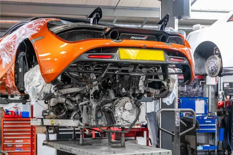Orange McLaren raised on a lift with rear engine access