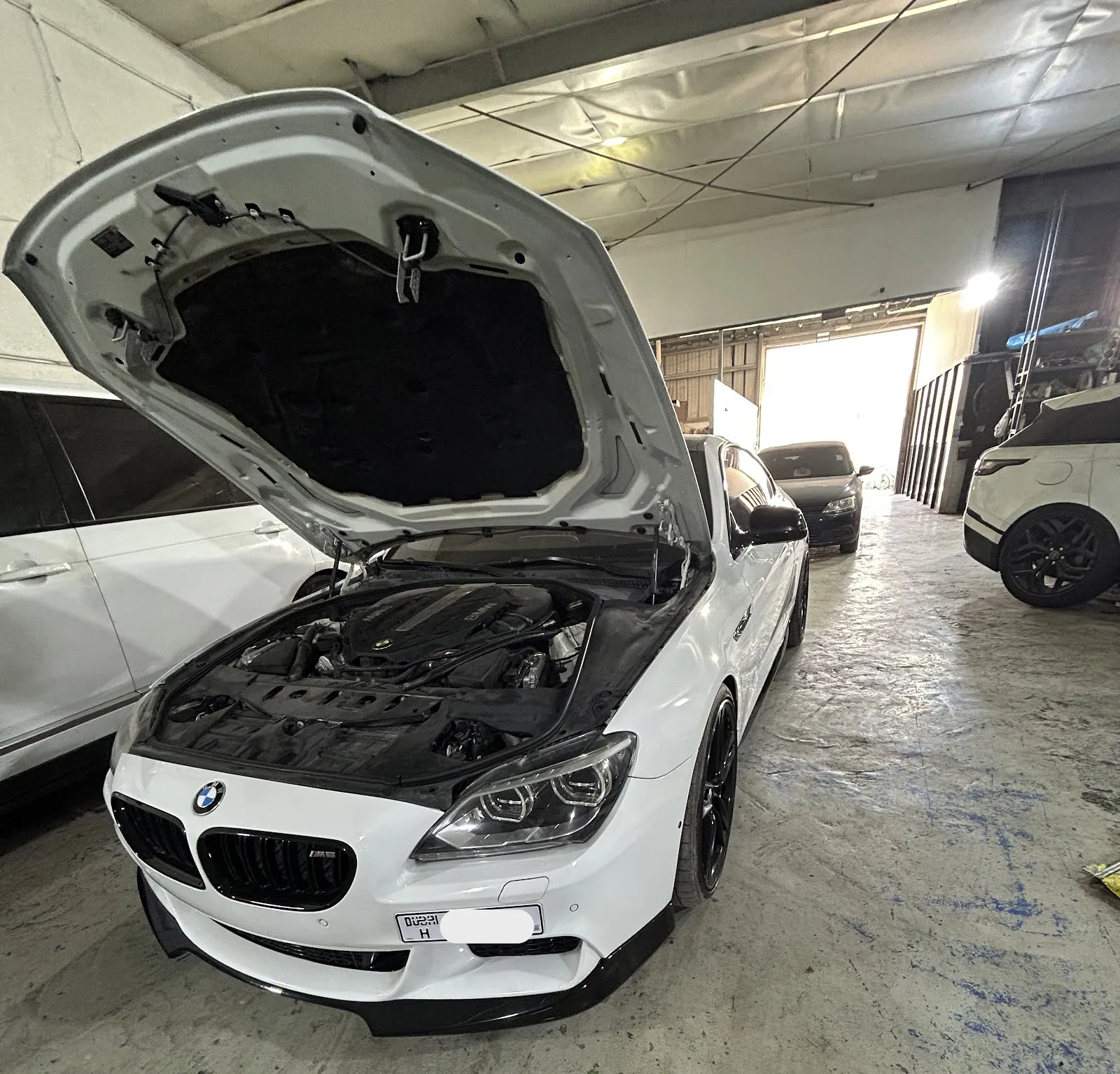 White BMW 6 Series with the bonnet open in the workshop