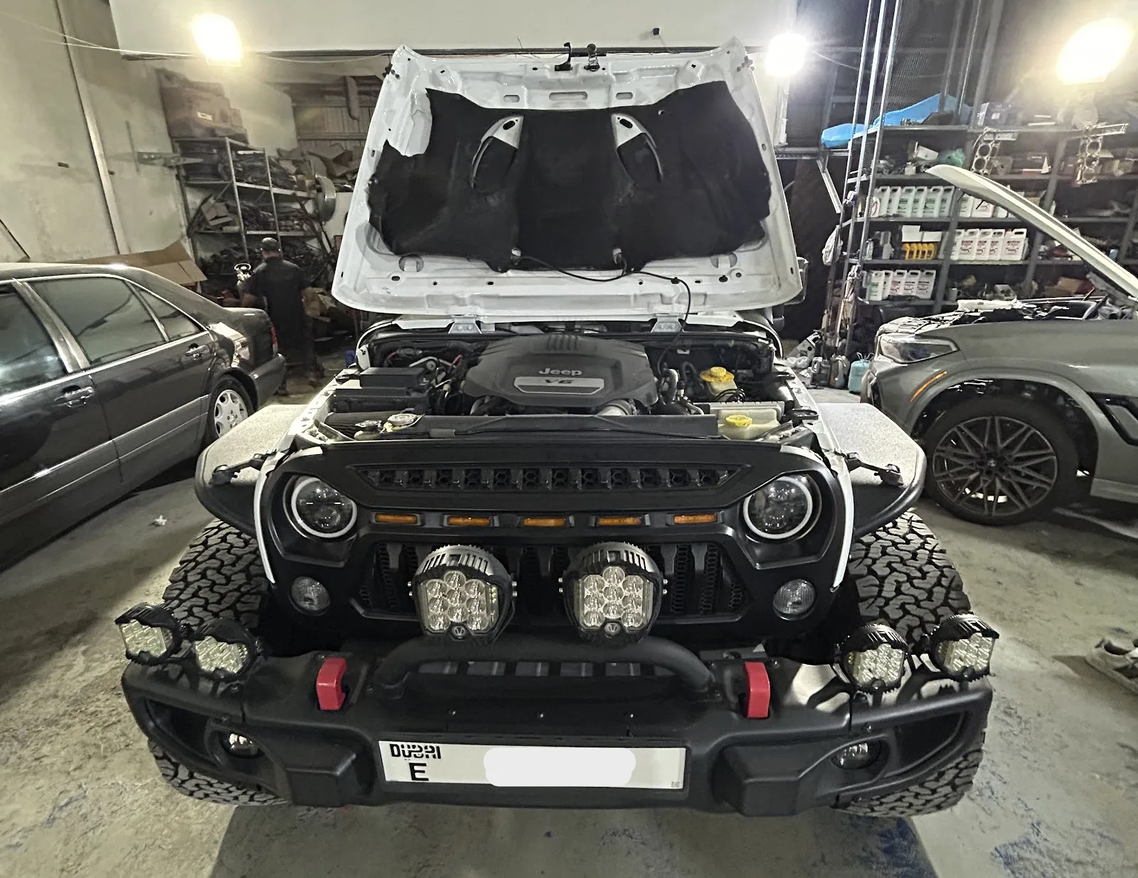 White Jeep Wrangler with auxiliary lighting in the workshop