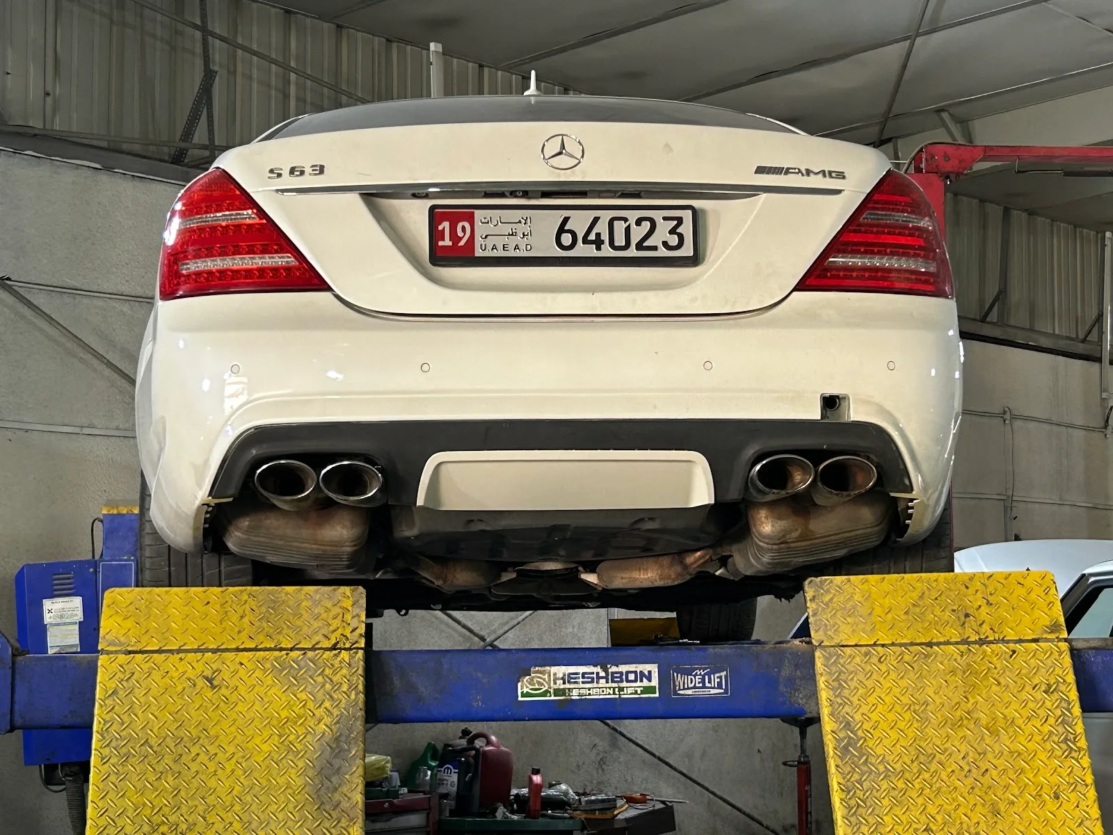 White Mercedes-AMG S 63 raised on the lift, exhaust view