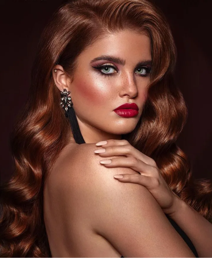 Salon client with glossy auburn waves and editorial makeup