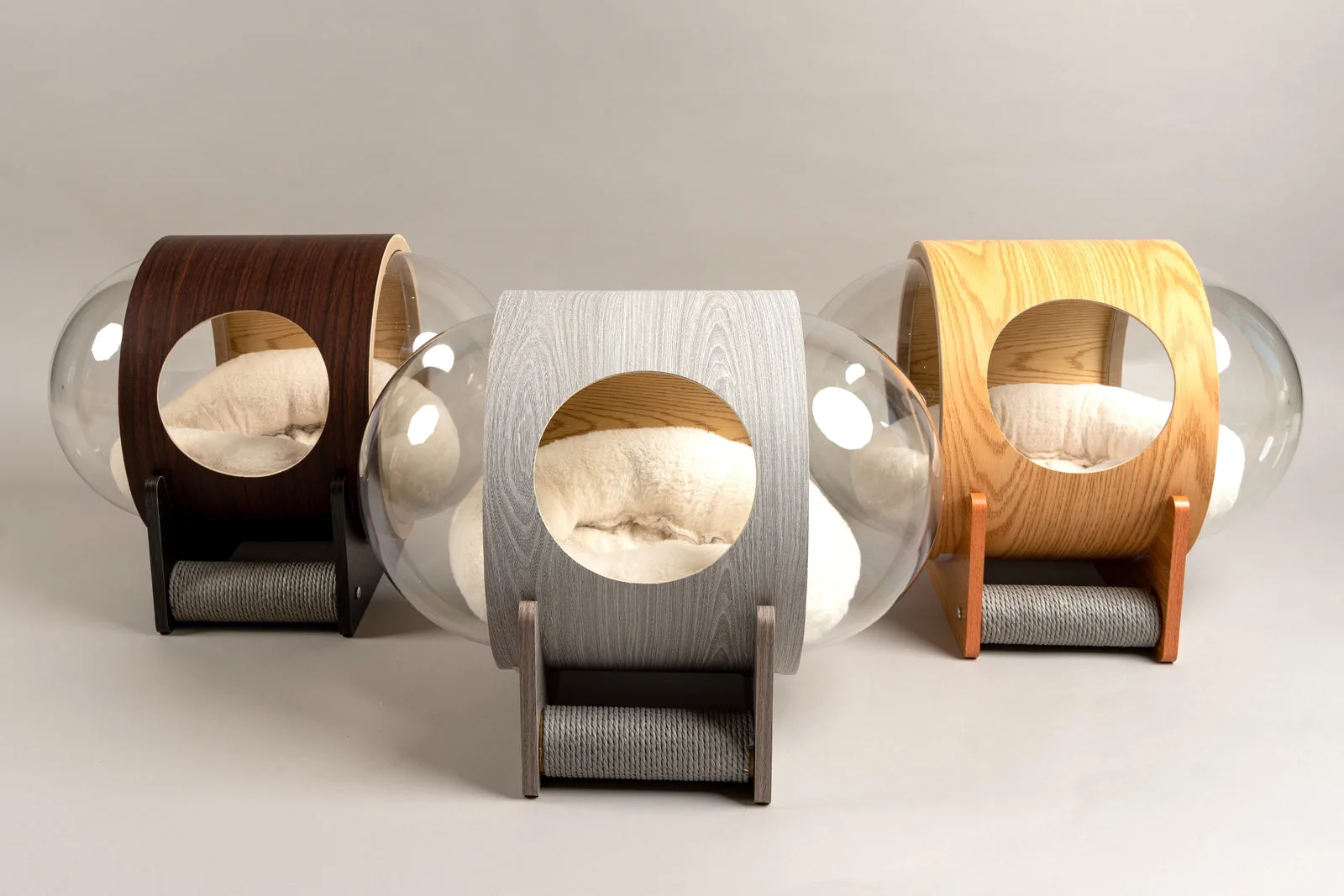Three wood-and-glass orbit cat beds in different finishes
