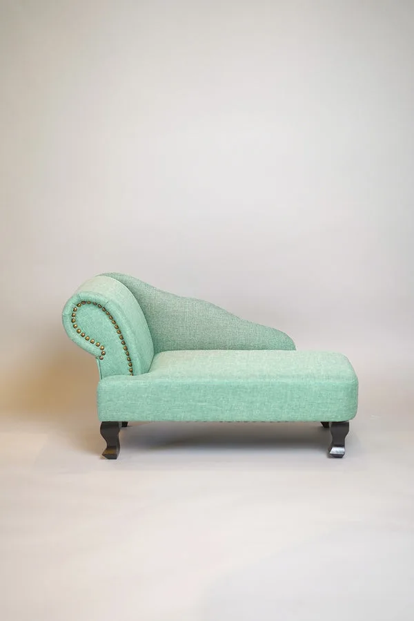 A boutique teal pet chaise styled in a bright room
