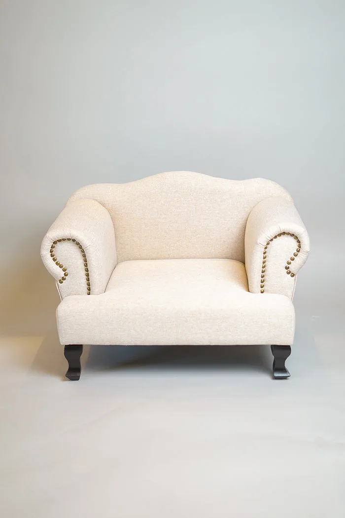 A cream upholstered pet armchair with studded detailing