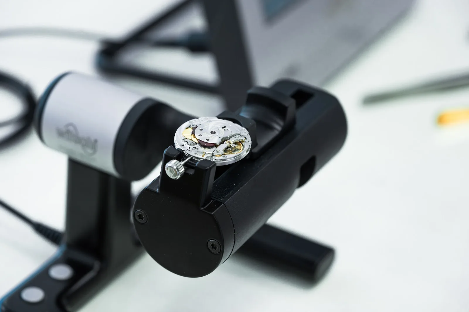 A bare watch movement held on a timing machine during servicing