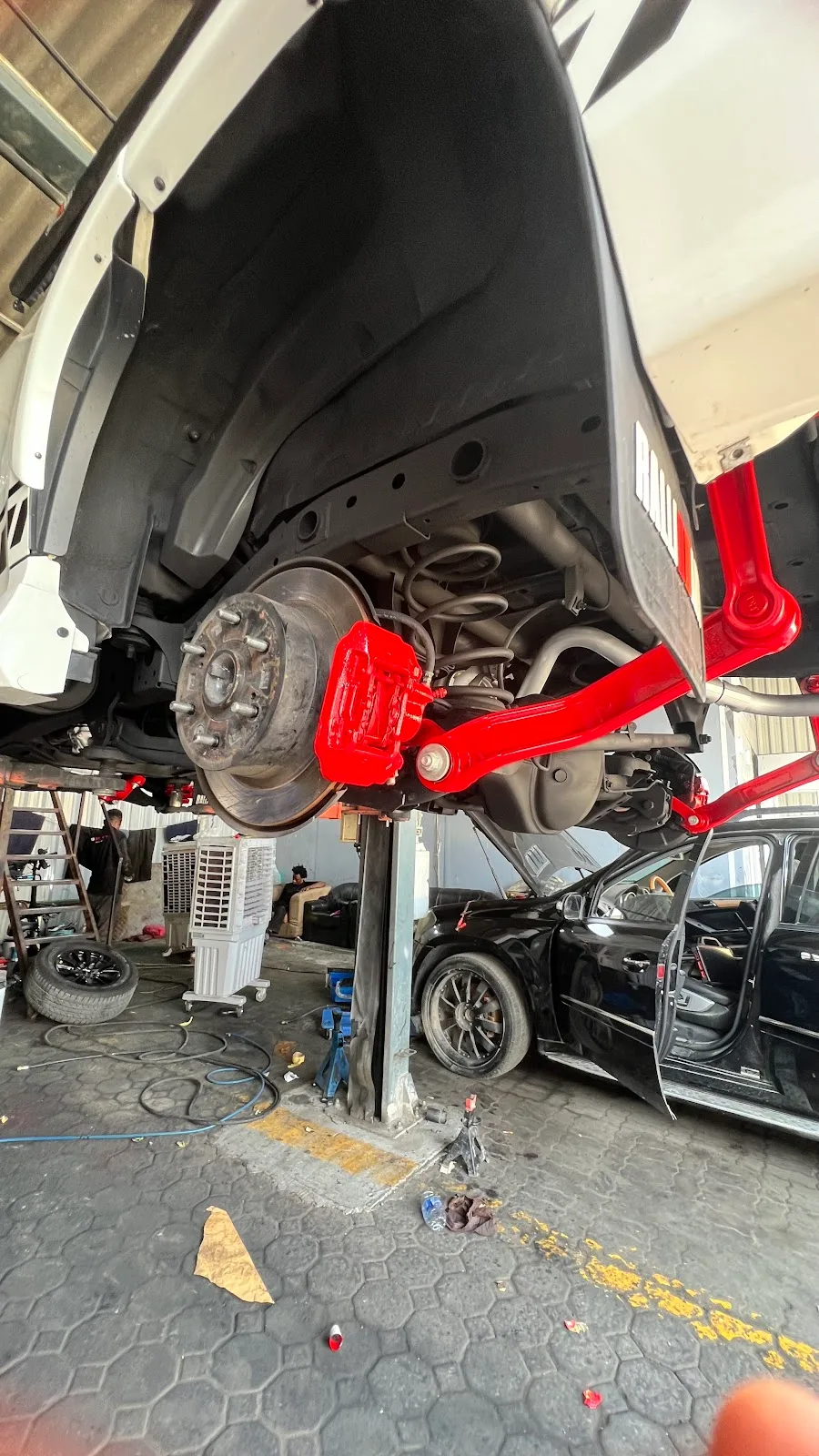Car raised on a lift showing a freshly painted red brake caliper and suspension