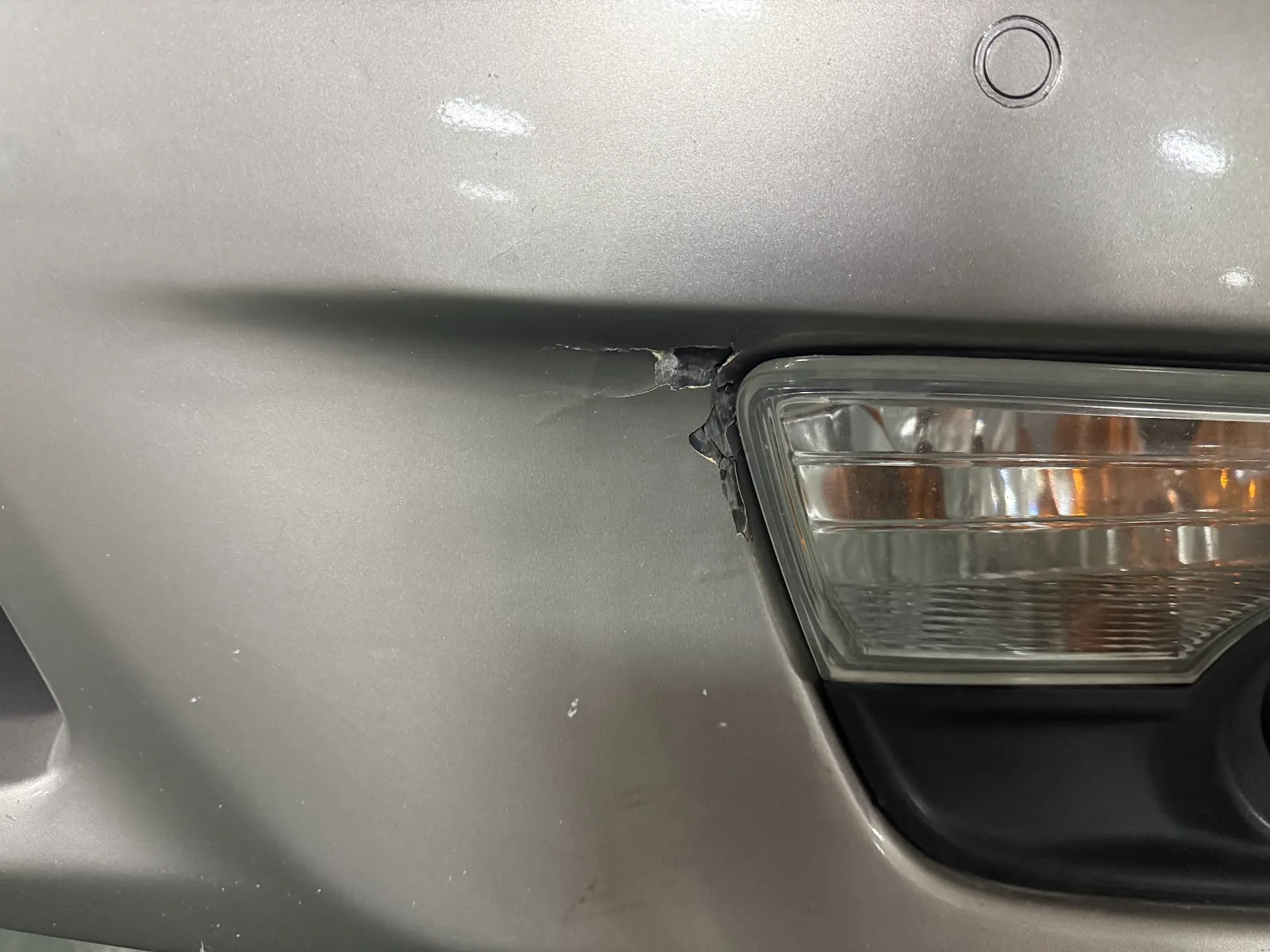 Close-up of bumper damage near a fog light