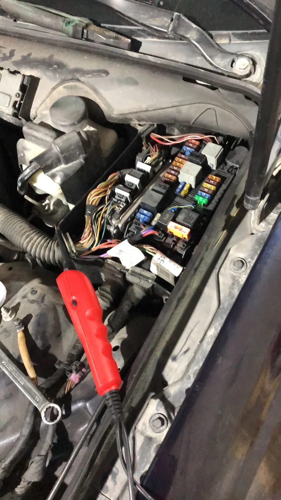 Technician testing a vehicle fuse box with a circuit tester