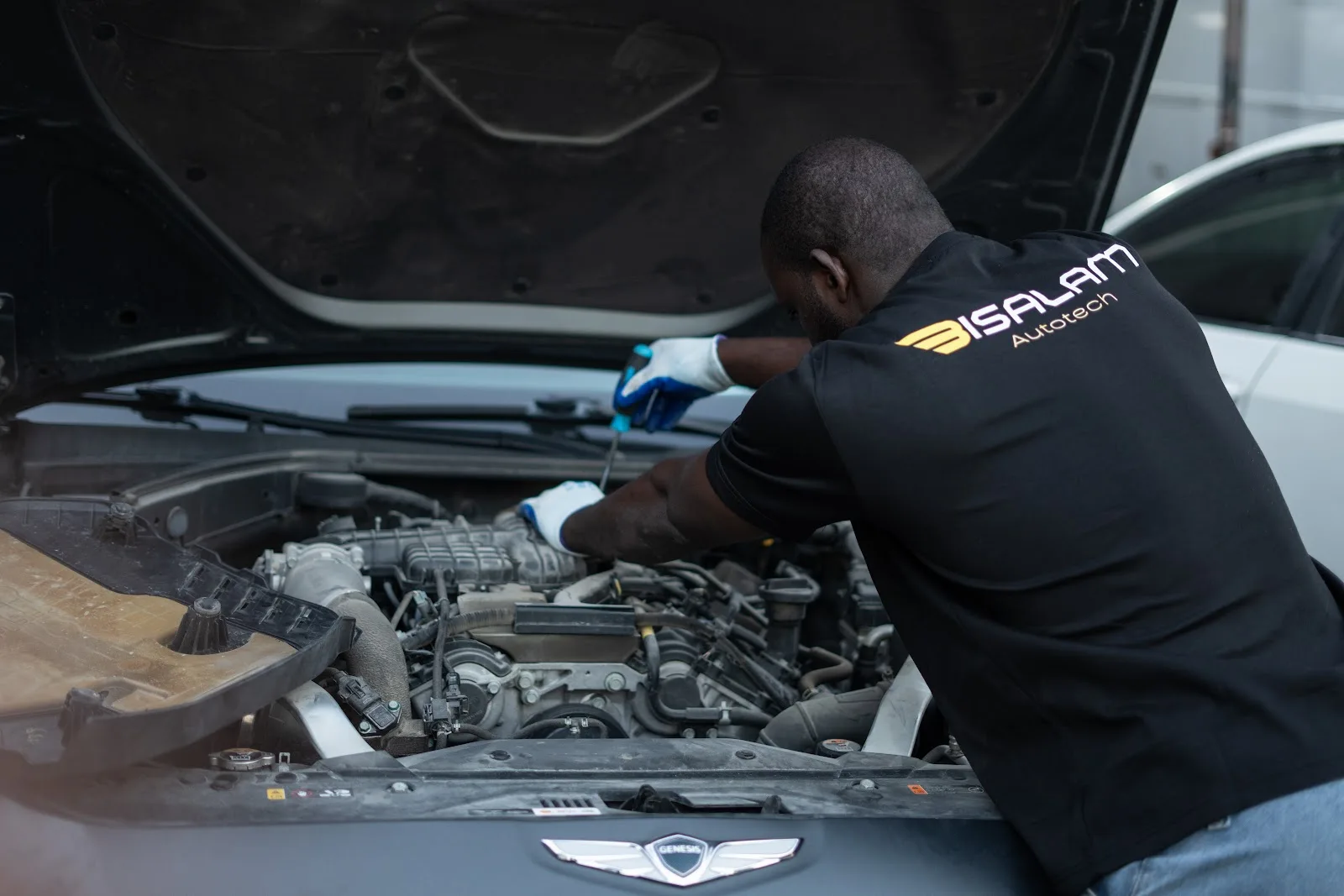 Bi Salam Autotech technician in branded shirt working on a car engine