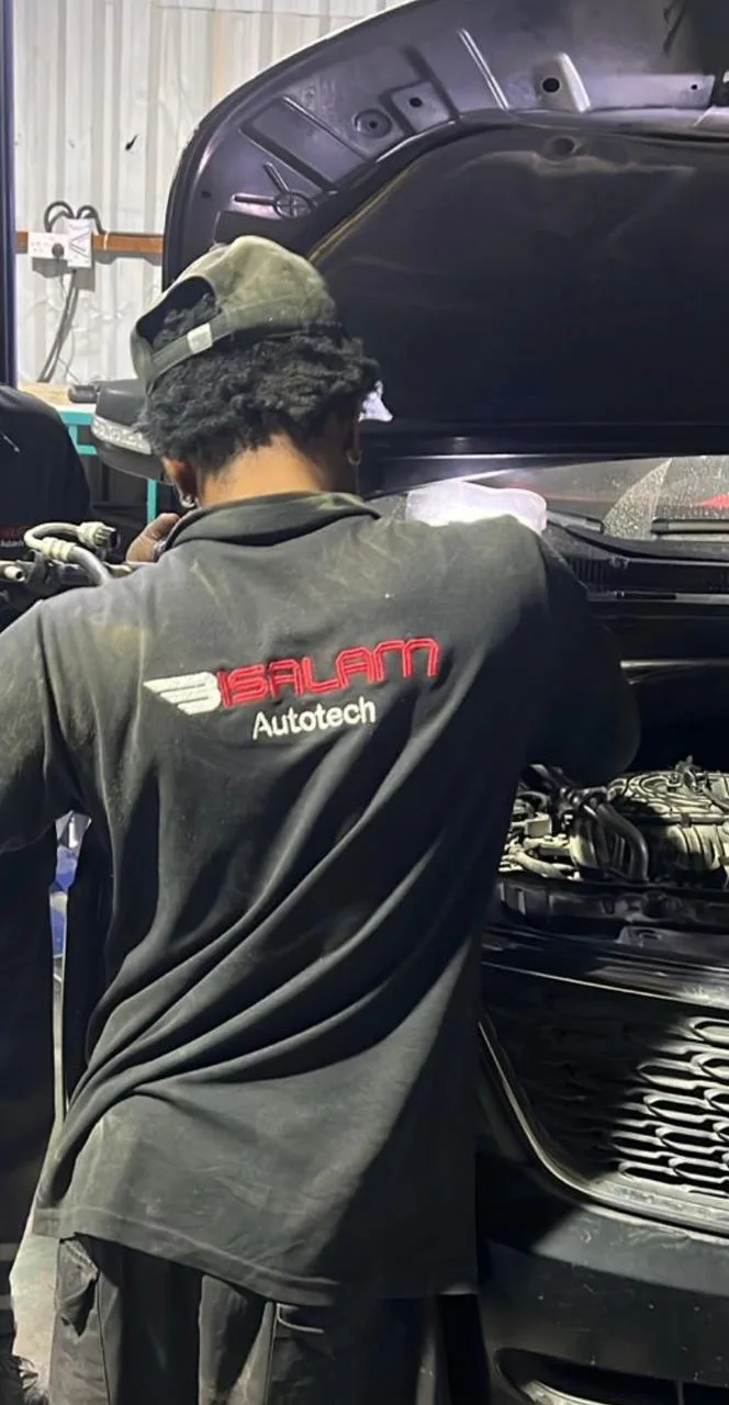 Bi Salam Autotech technician working under the bonnet on an engine