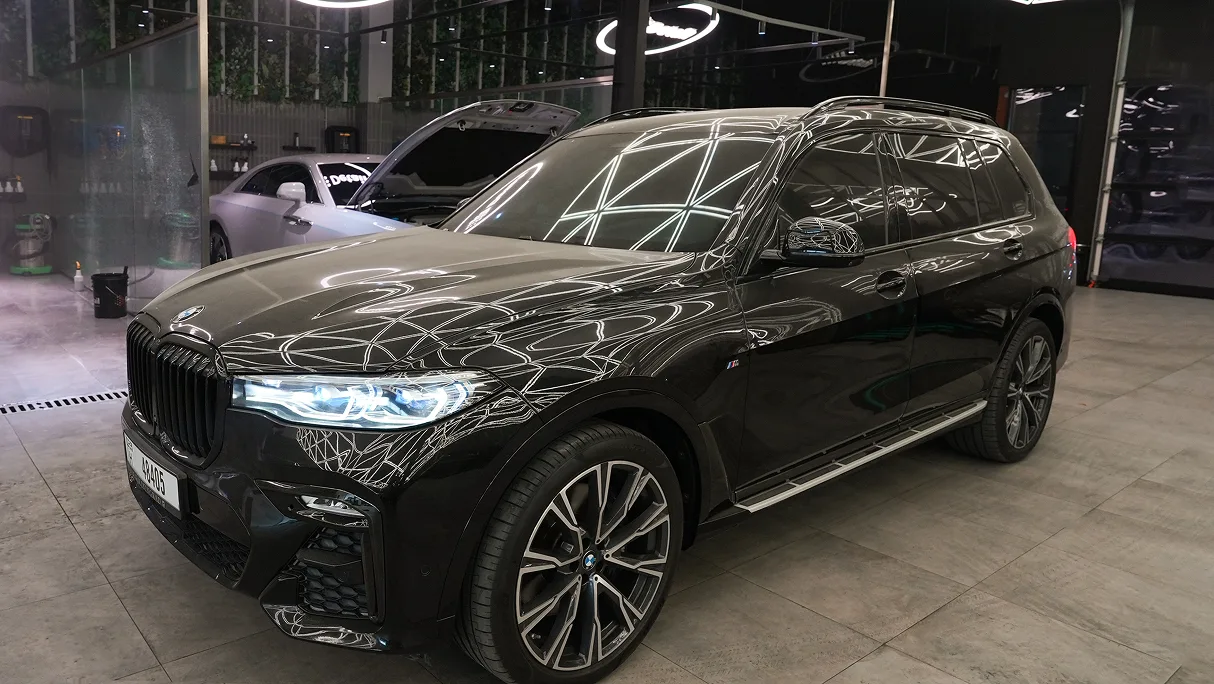 A black BMW X7 with dark tinted glass under studio lighting