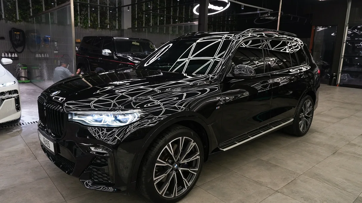 A black BMW X7 reflecting the studio's optic ceiling lights