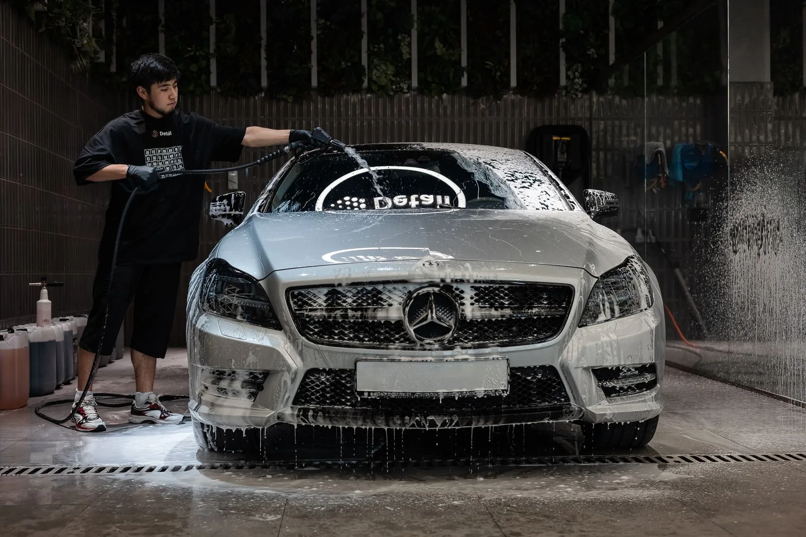 A luxury saloon covered in white snow foam being washed inside the Detail Dubai studio