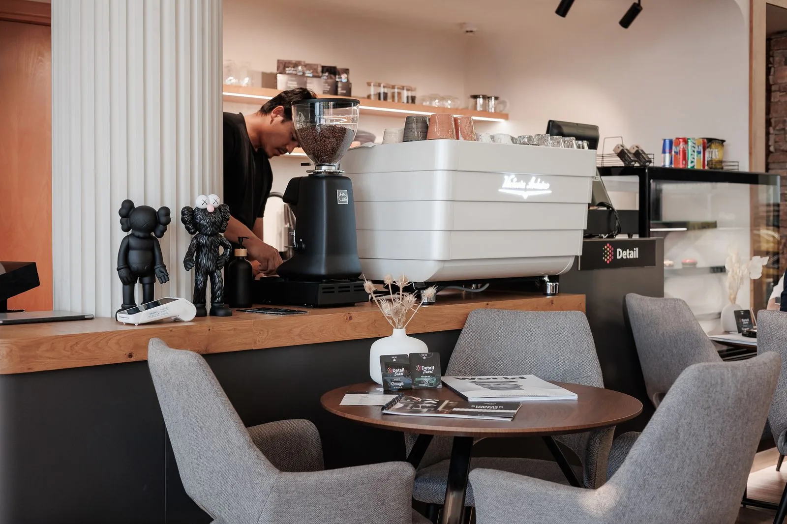 The Detail Dubai lounge with espresso machine, grey armchairs and a coffee table
