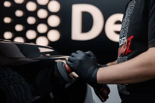 A technician machine-polishing a glossy black panel