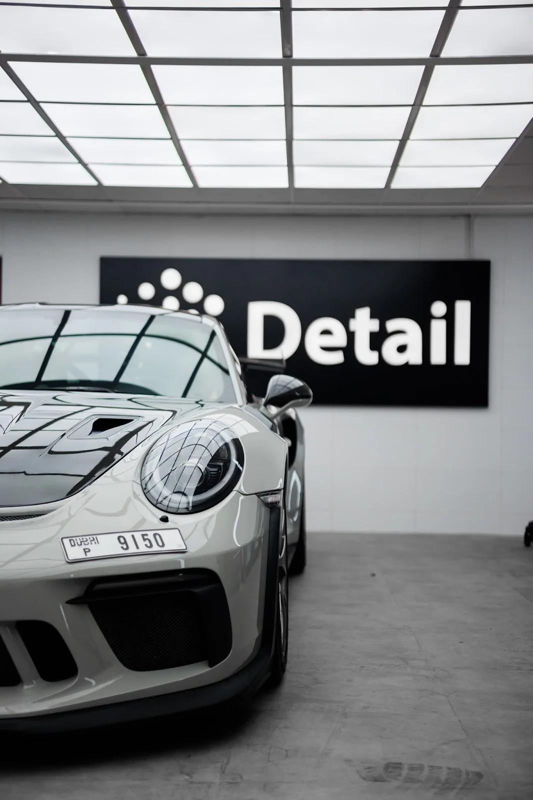 A grey Porsche 911 GT3 parked in front of the Detail studio sign