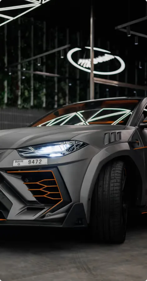 A grey widebody Lamborghini Urus with orange accents